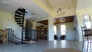 Amplia sala de estar con una escalera en espiral, una estantería y un comedor.