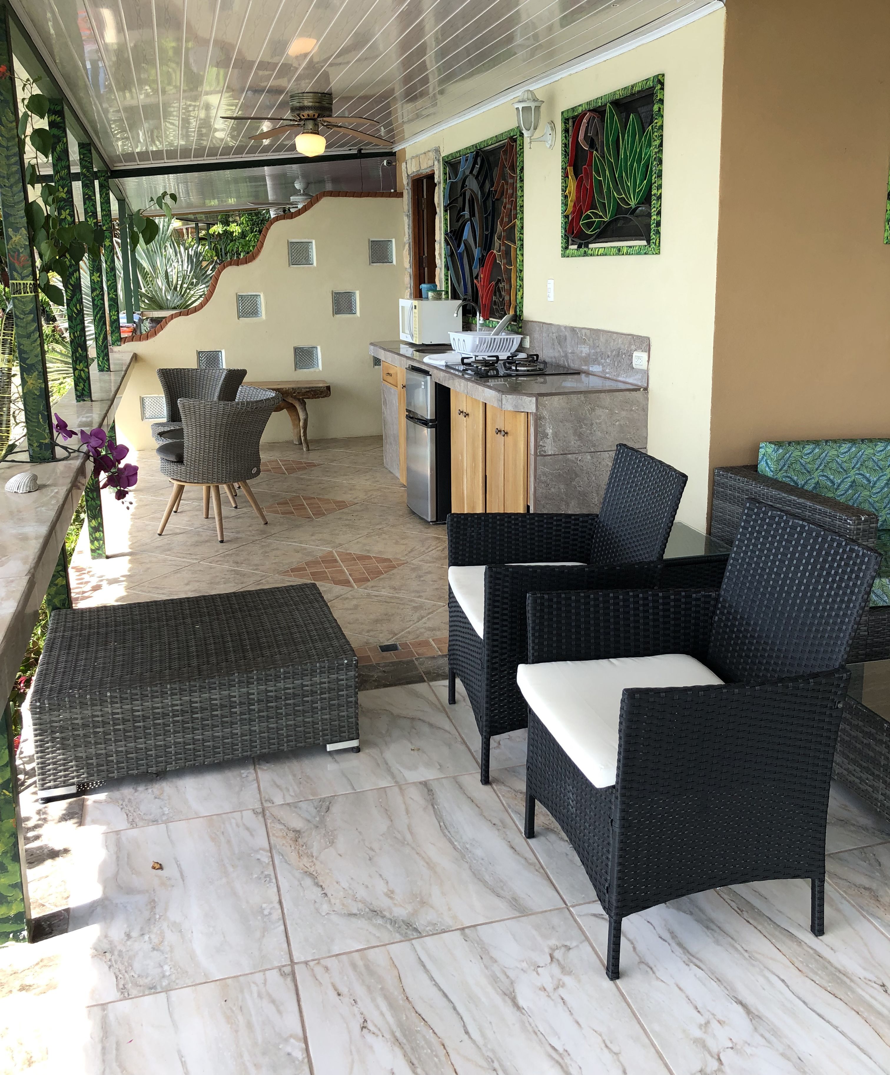 A covered outdoor area with a kitchen, seating, and a staircase.