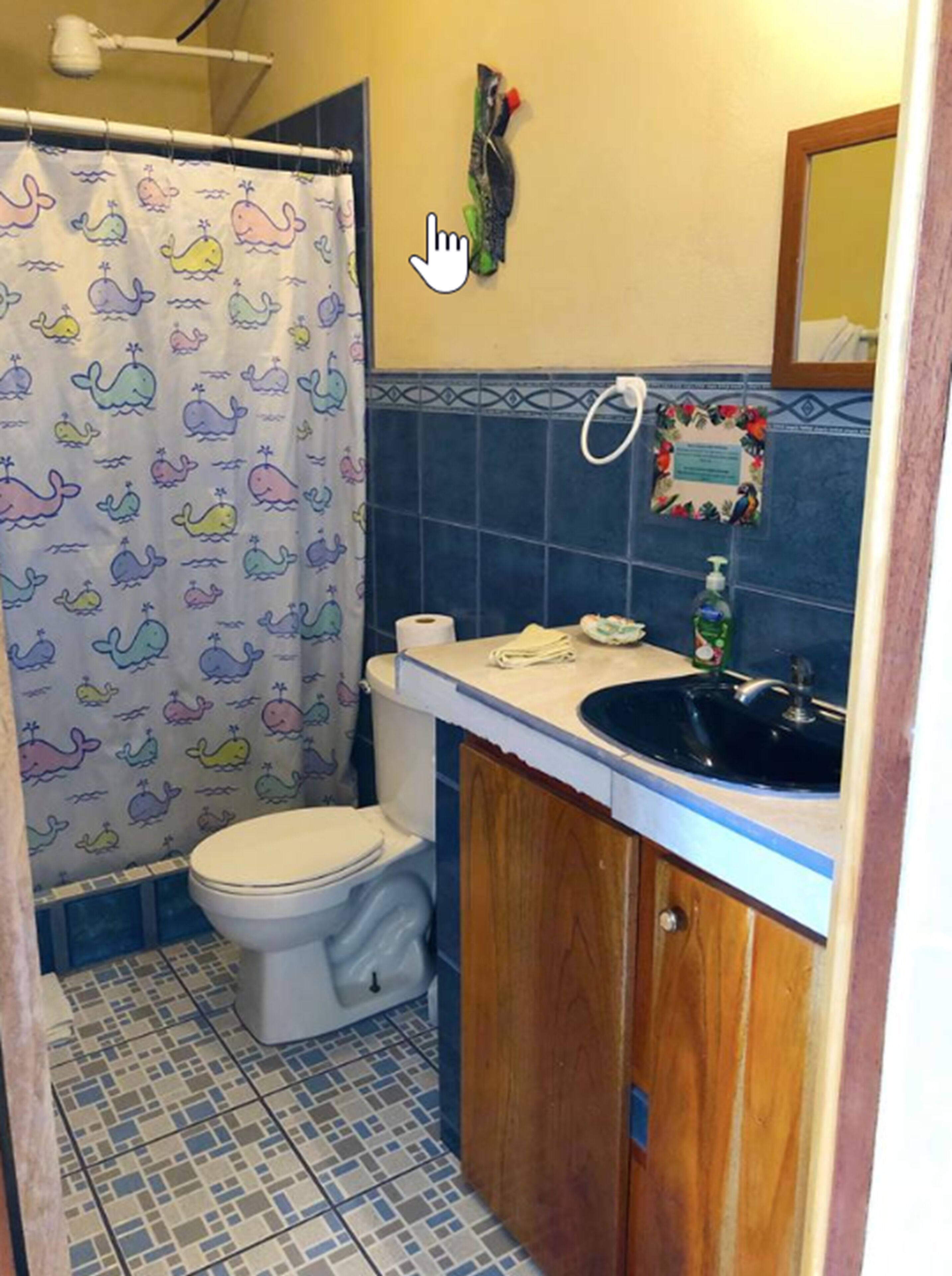 A bathroom with a toilet, a sink, and a shower curtain with whale patterns.