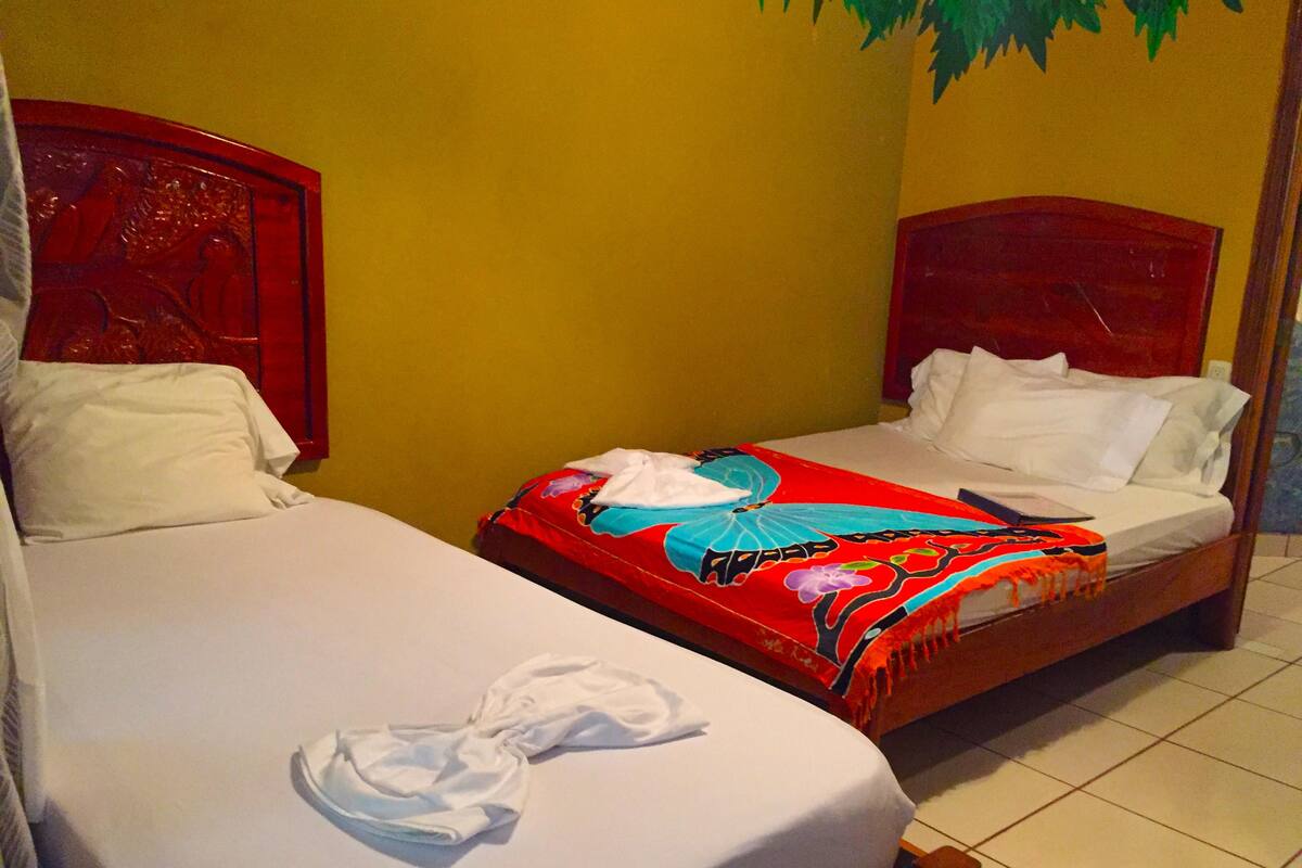 Two single beds with wooden headboards in a room with yellow walls.