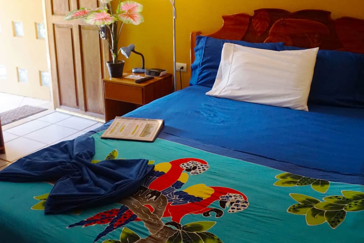 A room with a bed, a nightstand, a lamp, a wall mural, and a door.