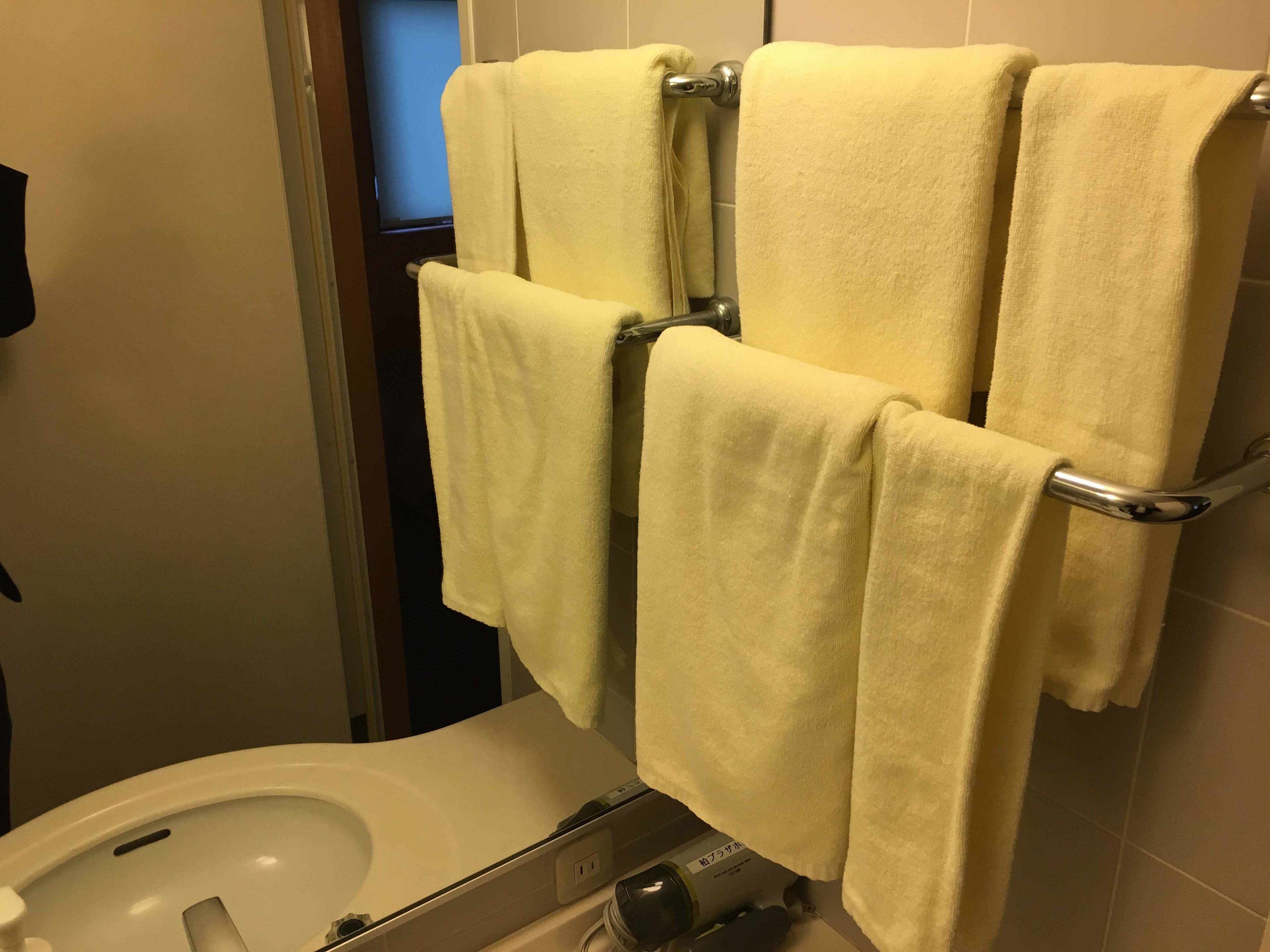 A bathroom with a toilet, a towel rack with four towels, and a visible water heater.
