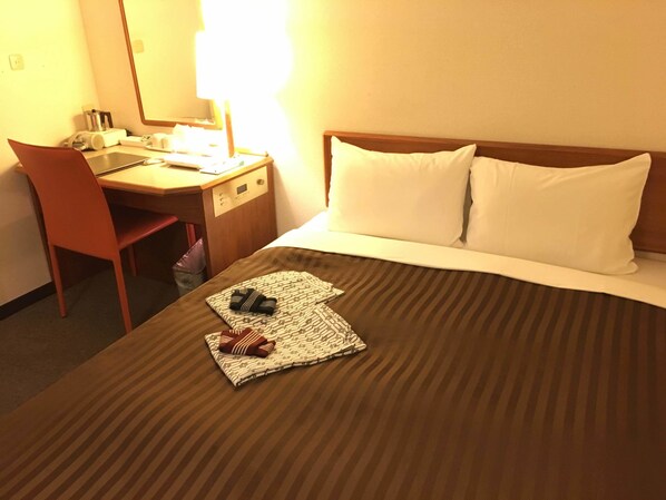 Une chambre d’hôtel avec un lit, un bureau, une chaise et une table de chevet.