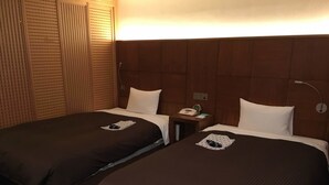 A hotel room with two single beds, each with a pillow and a small table with a phone and a clock. - Kashiwa Plaza Hotel (Kashiwa)