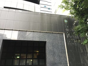 Une façade moderne avec une entrée imposante et une enseigne indiquant qu’il s’agit d’un hôtel.