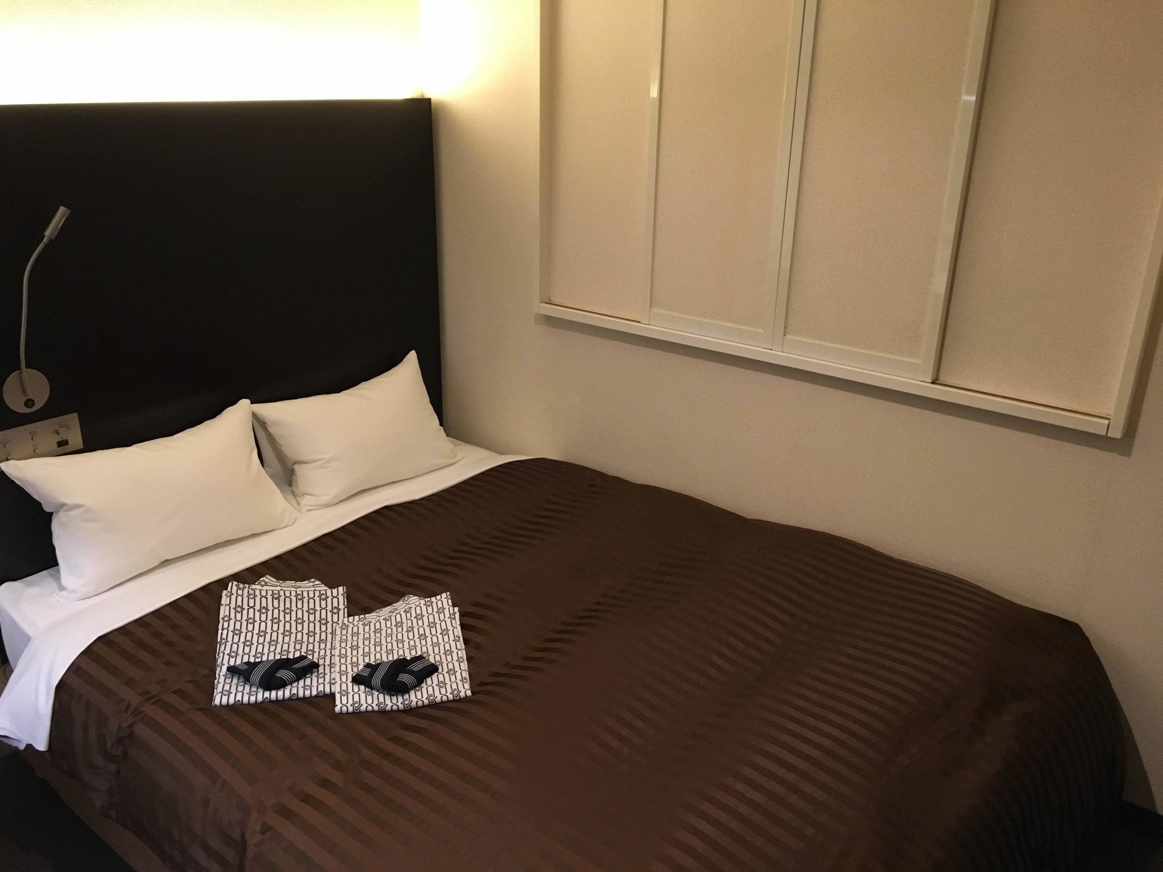 Una cama bien hecha con una colcha marrón y dos almohadas blancas.