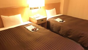 A hotel room with two beds, each with a pillow and a folded towel. There is a nightstand with a lamp between the beds. - Kashiwa Plaza Hotel Annex (Kashiwa)