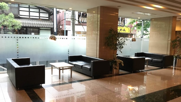 A lobby with a seating area, a reception desk, and a view of the outside. - Kashiwa Plaza Hotel Annex (Kashiwa)