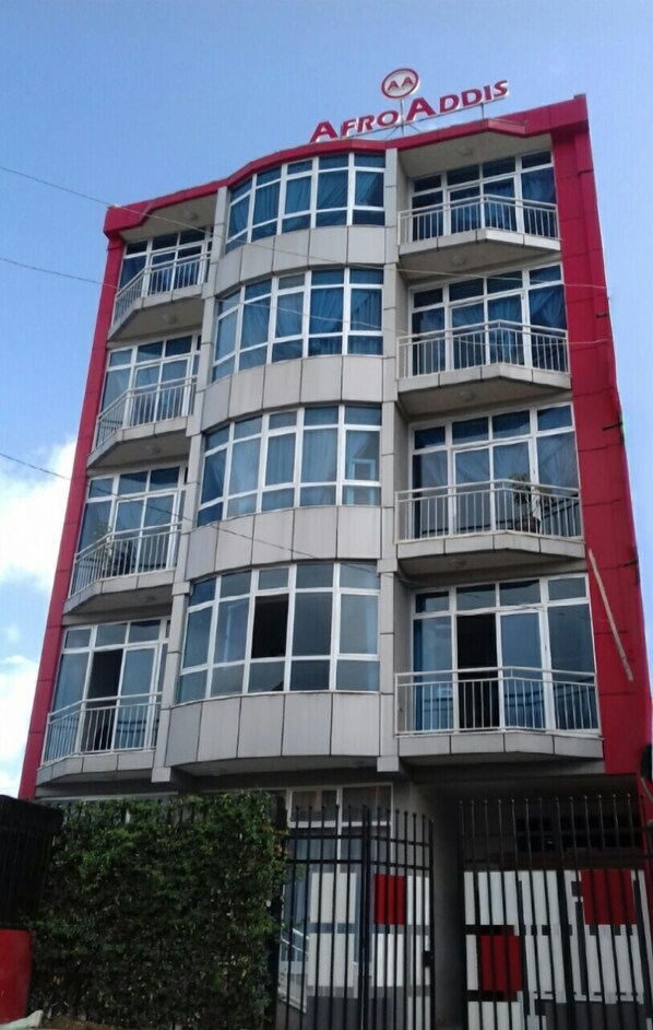 A multi-story building with a red and white facade, balconies, and a sign reading 'AFRO ADDIS' at the top.