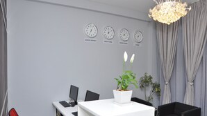 A modern office with a white desk, black chairs, a potted plant, and clocks labeled with city names. - Afroaddis Hotel Apartment (Addis Ababa)