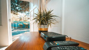 A wooden desk with a potted plant, a projector, and two remote controls. - Surf Motel (eMdloti)