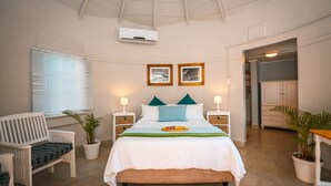 A bedroom with a bed, bedside tables, a chair, a potted plant, and a ceiling fan. - Surf Motel (eMdloti)