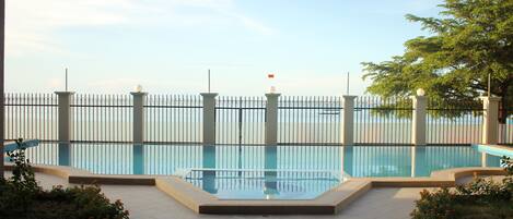 Una piscina al aire libre, sombrillas, sillones reclinables de piscina