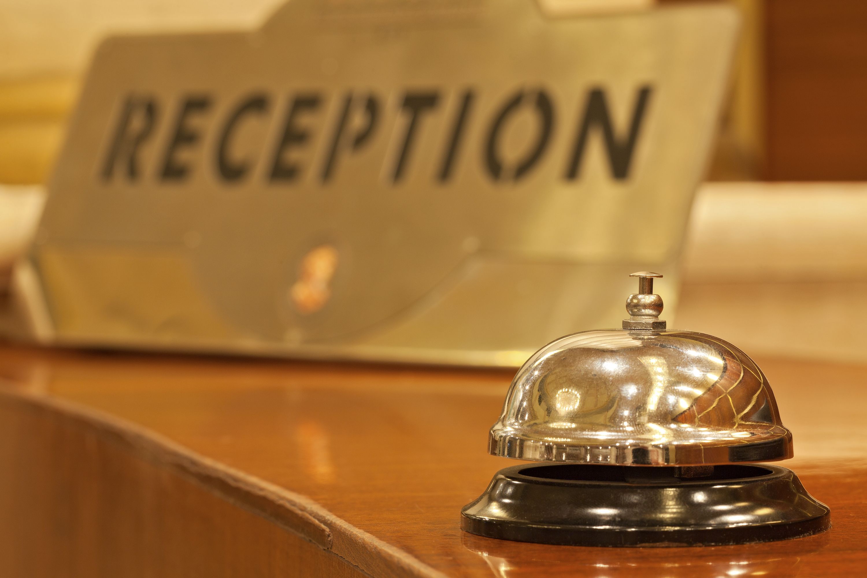 A reception area with a sign labeled "RECEPTION" and a bell on a wooden counter.