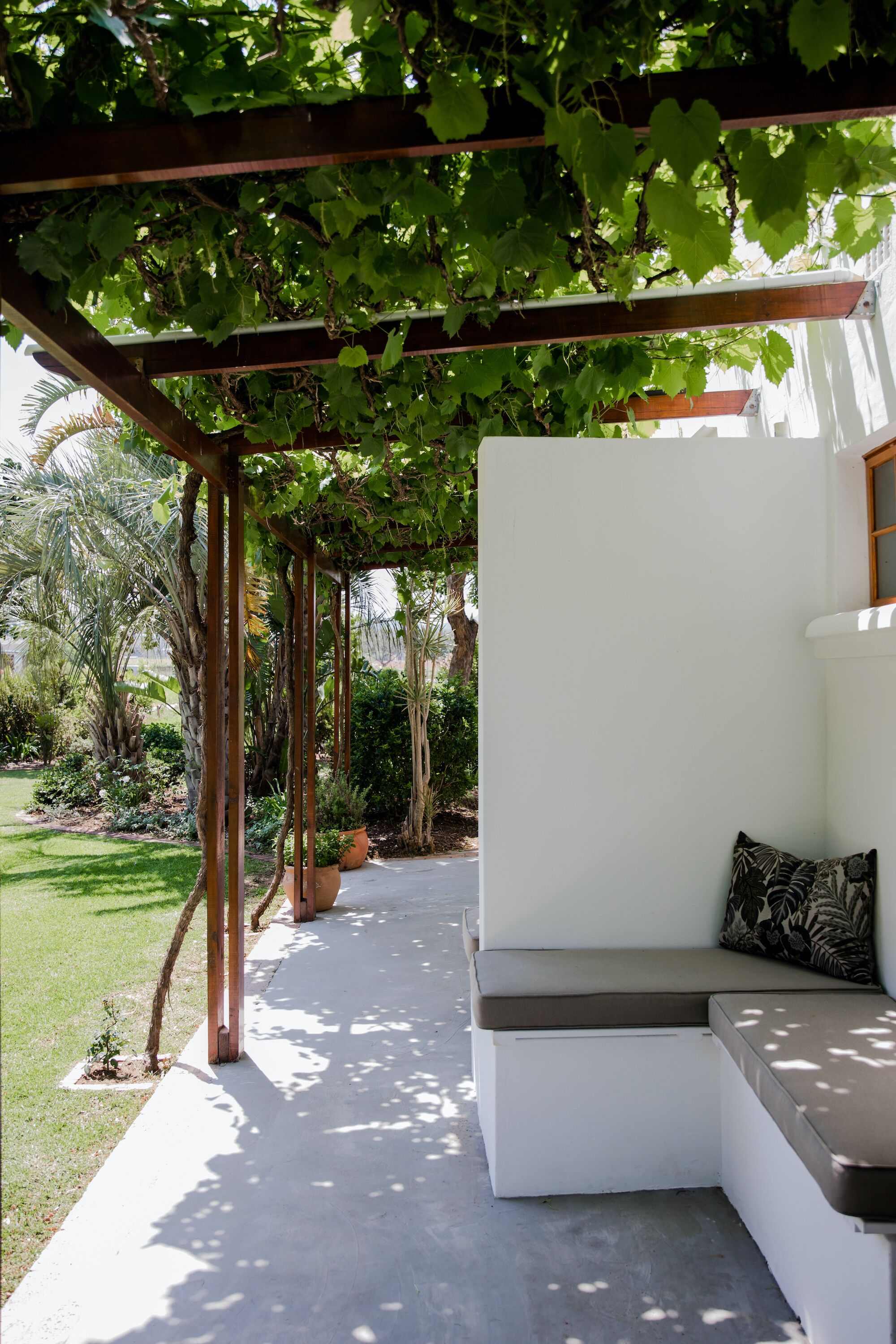 A covered outdoor seating area with a white bench and a pergola overhead.