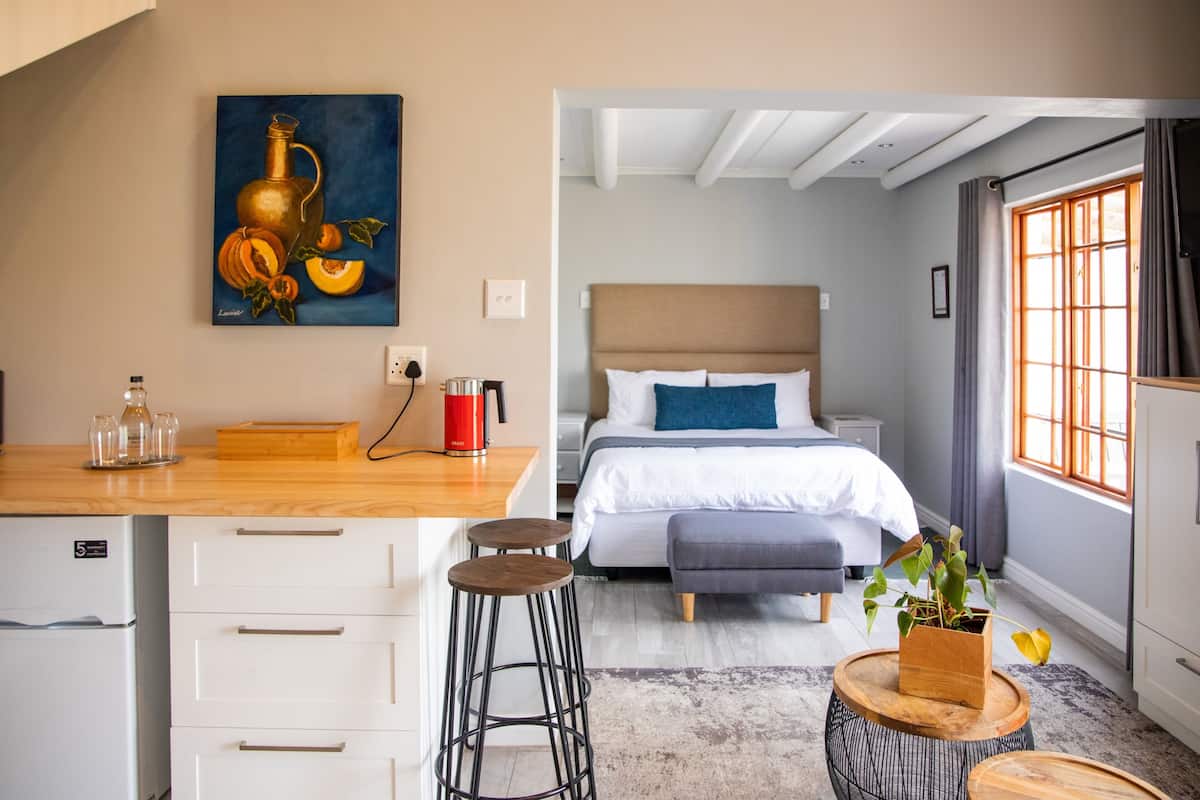 Ein modernes Zimmer mit Bett, Nachttisch und einem Bild von Obst und Gemüse an der Wand.