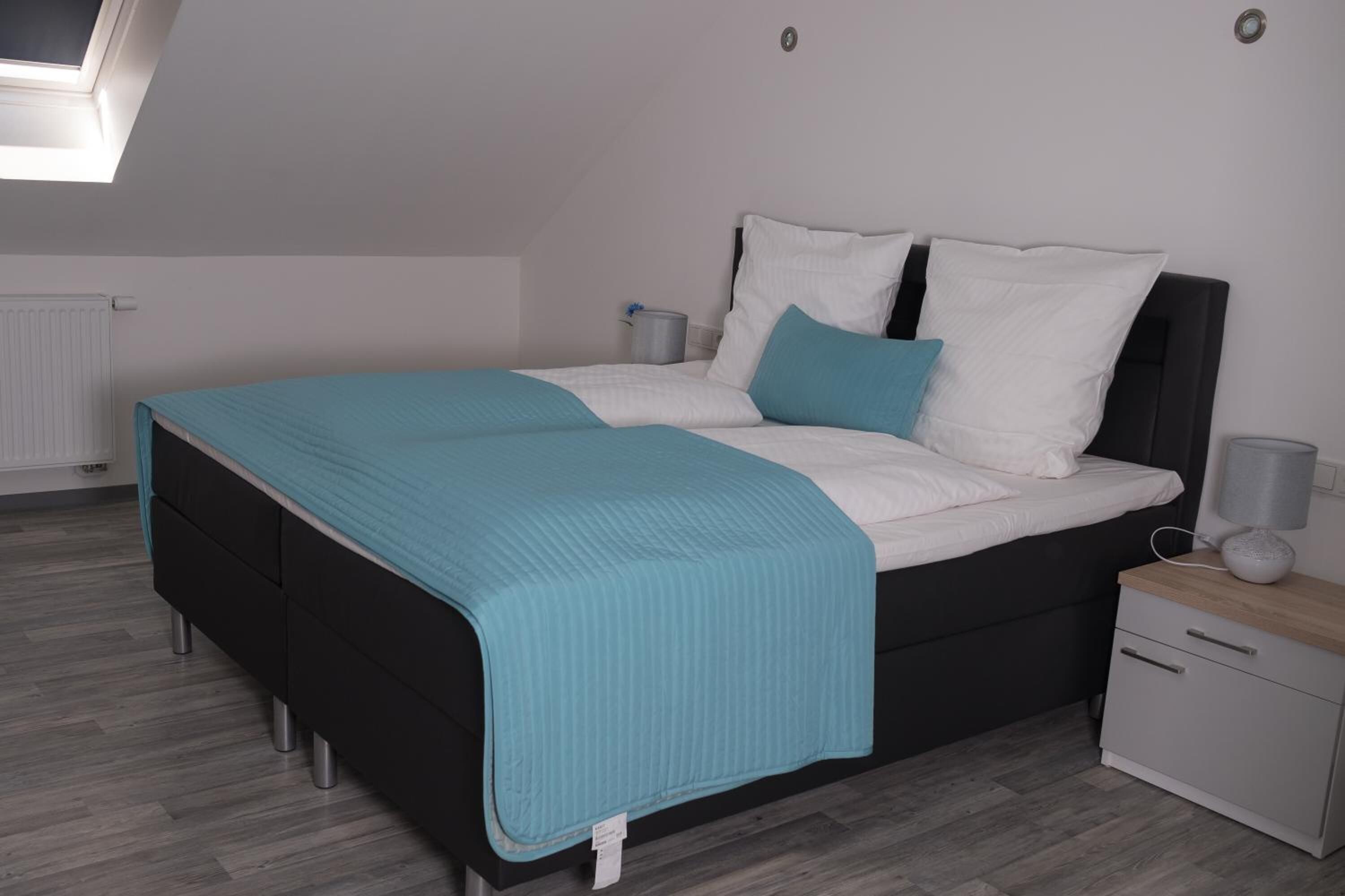 Une chambre moderne avec un lit, des tables de chevet et une lucarne.