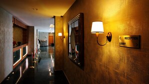 Zona de recepción de hotel con piso pulido, mostrador de recepción y señalización que indica el camino al vestíbulo.