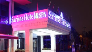 Exterior del Hotel & Spa Sarissa con señalización iluminada y un restaurante McDonald's contiguo.