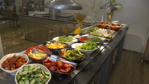 Un bufé con diversas opciones de comida, como ensaladas, verduras y frutas.