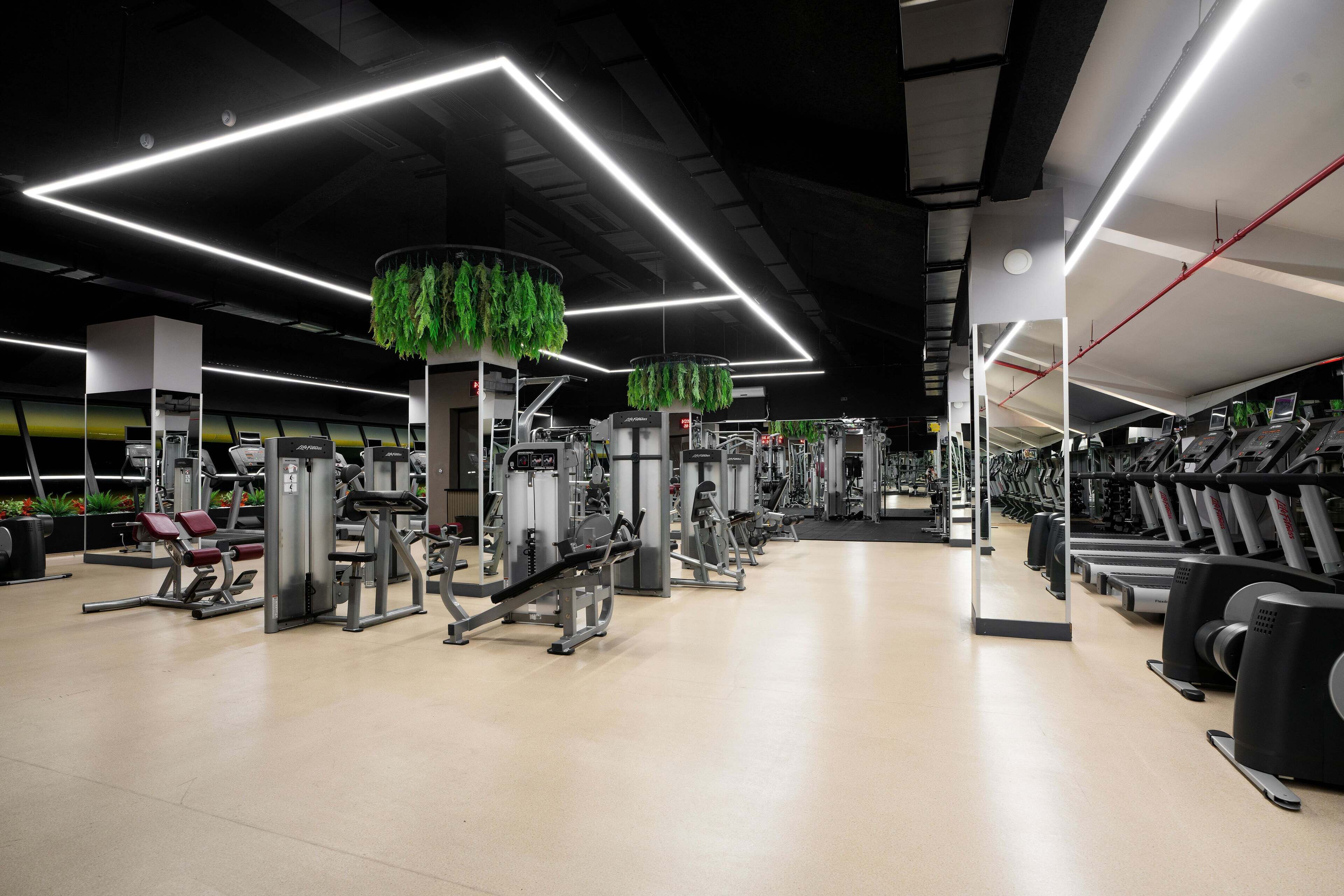 Un gimnasio con diversas máquinas de ejercicio, cintas de correr y un diseño moderno y limpio.