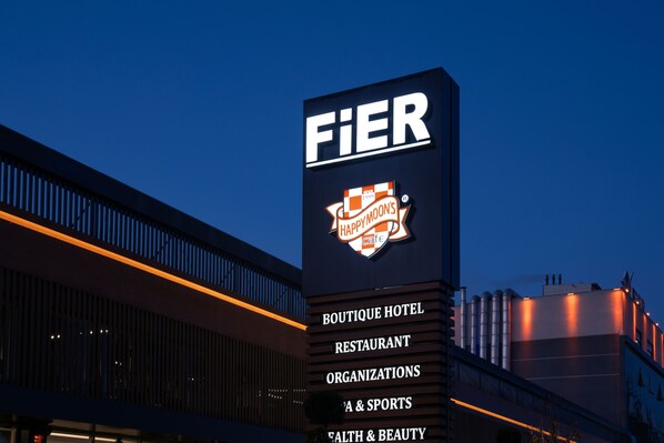 Un letrero de hotel con los logotipos 'FIER' y 'HAPPYMOON'S cafe', indicando un hotel boutique con cafetería.