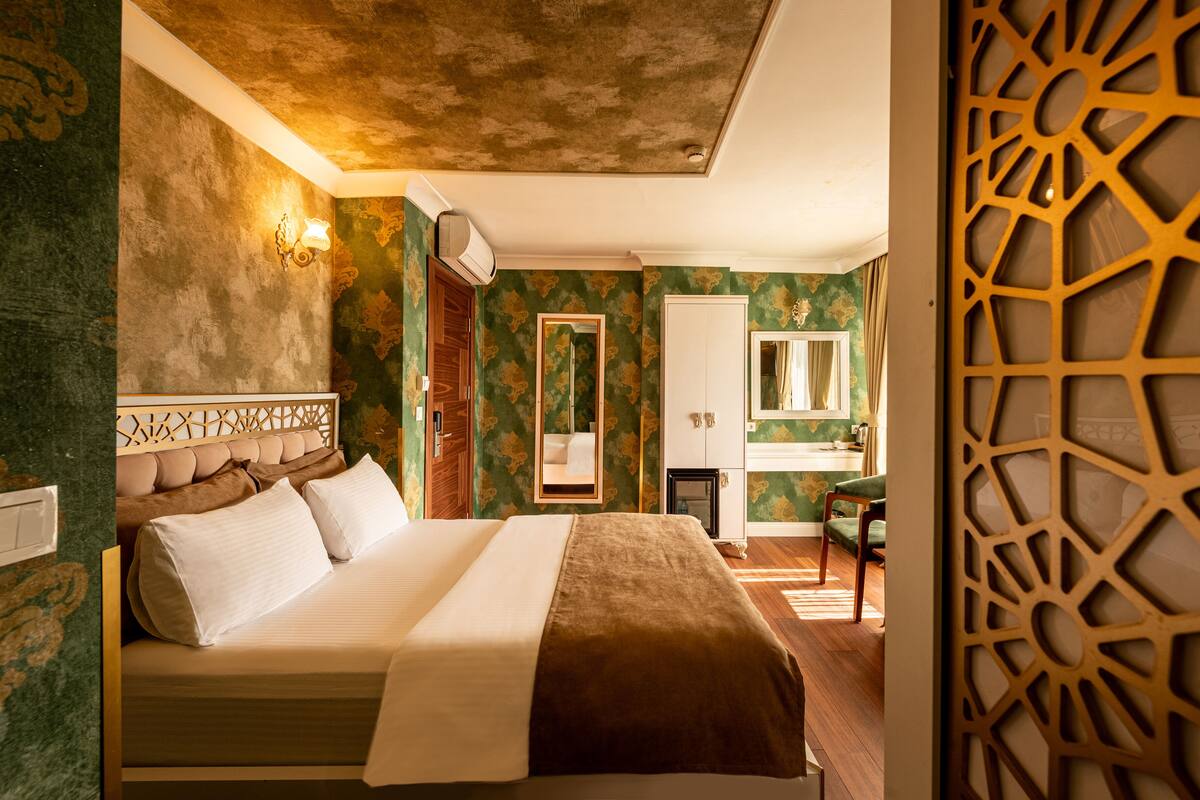 A hotel room with a bed, a mirror, a wardrobe, and a decorative screen.