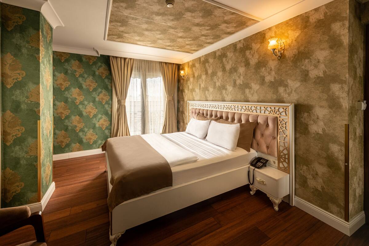 A bedroom with a large bed, a bedside telephone, and a wall-mounted light fixture.