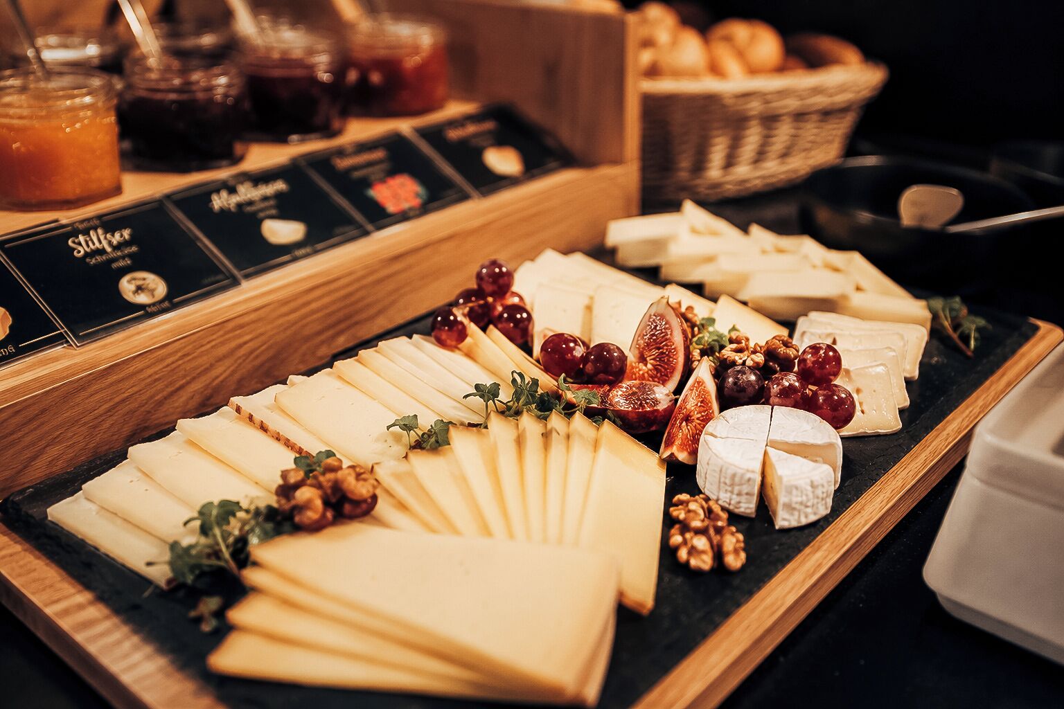 A charcuterie board with various cheeses, fruits, and nuts.