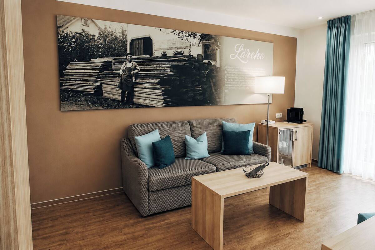 A modern hotel room with a sofa, coffee table, and a cabinet.