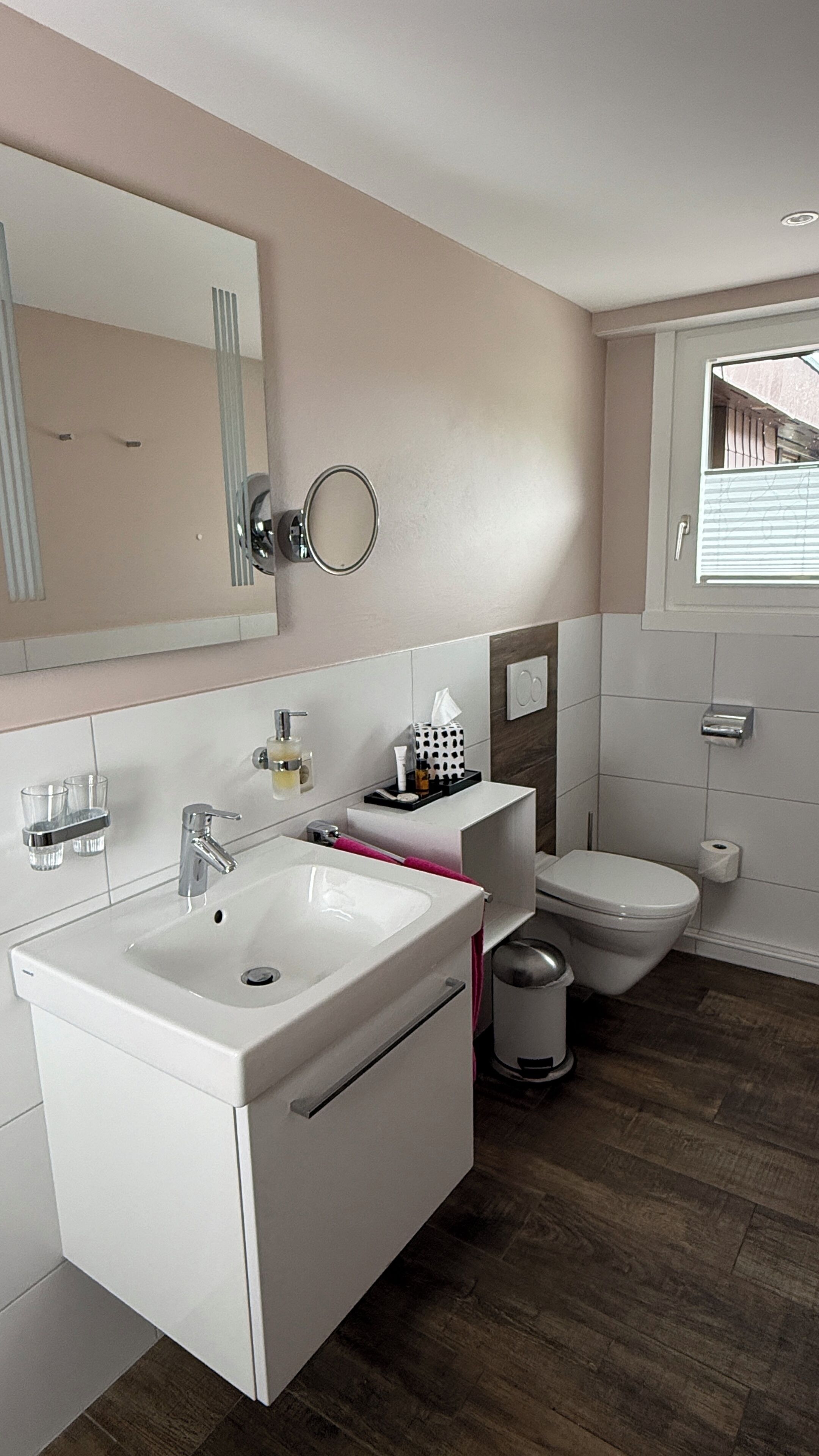 A modern bathroom with a white sink, mirror, and toilet.