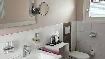 A modern bathroom with a white sink, mirror, and toilet.