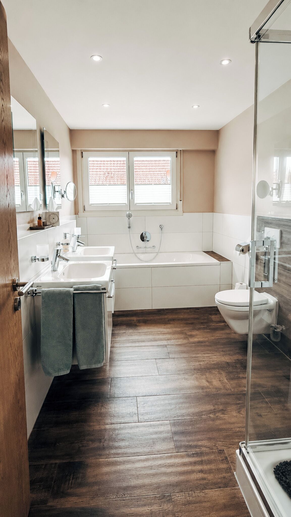 Un baño moderno con bañera, inodoro y dos lavabos.