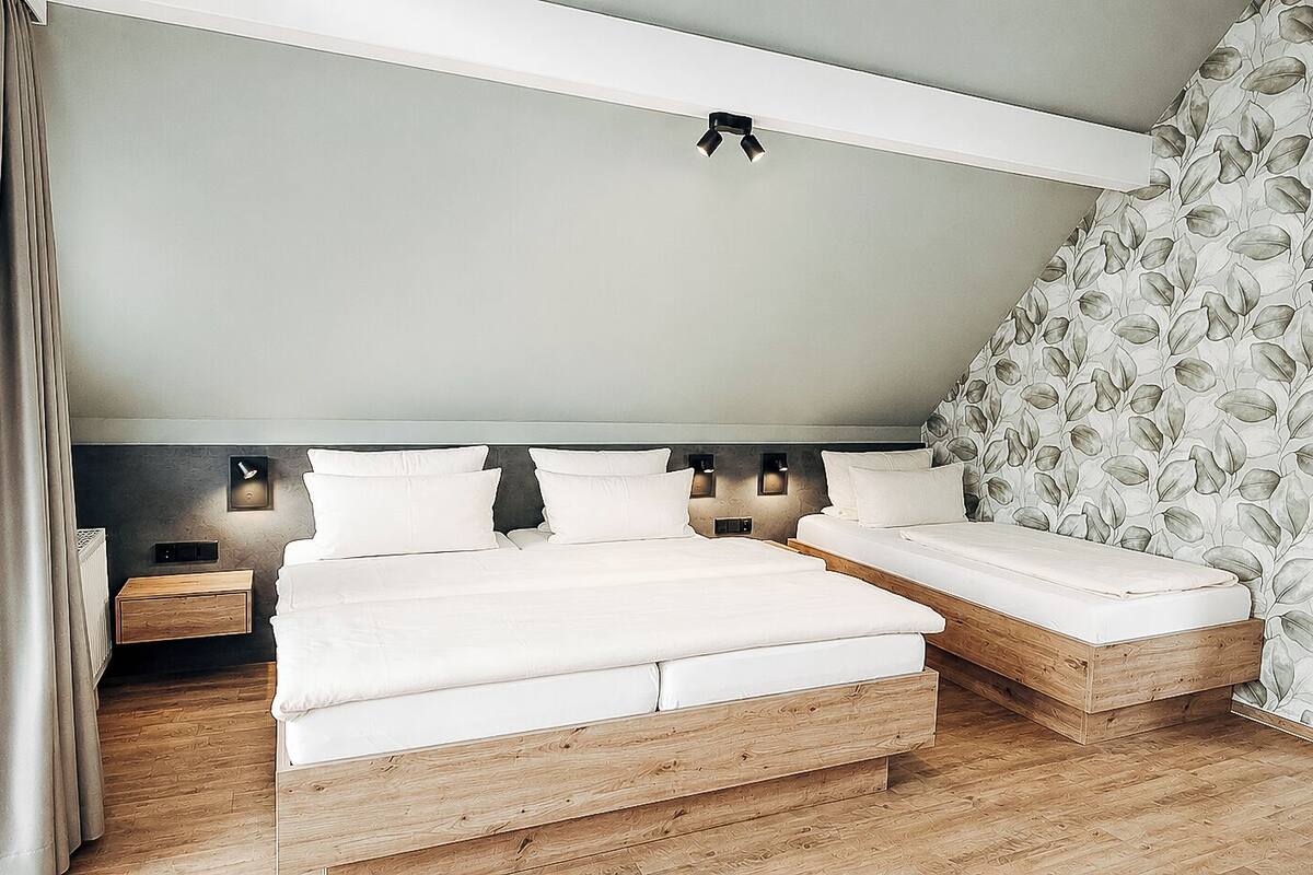 A bedroom with a bed, bedside tables, and a wall-mounted light fixture.