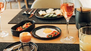 A dining table with plates of food, a glass of wine, and a glass of juice. - Hotel Garni Bergblick (Biberach)