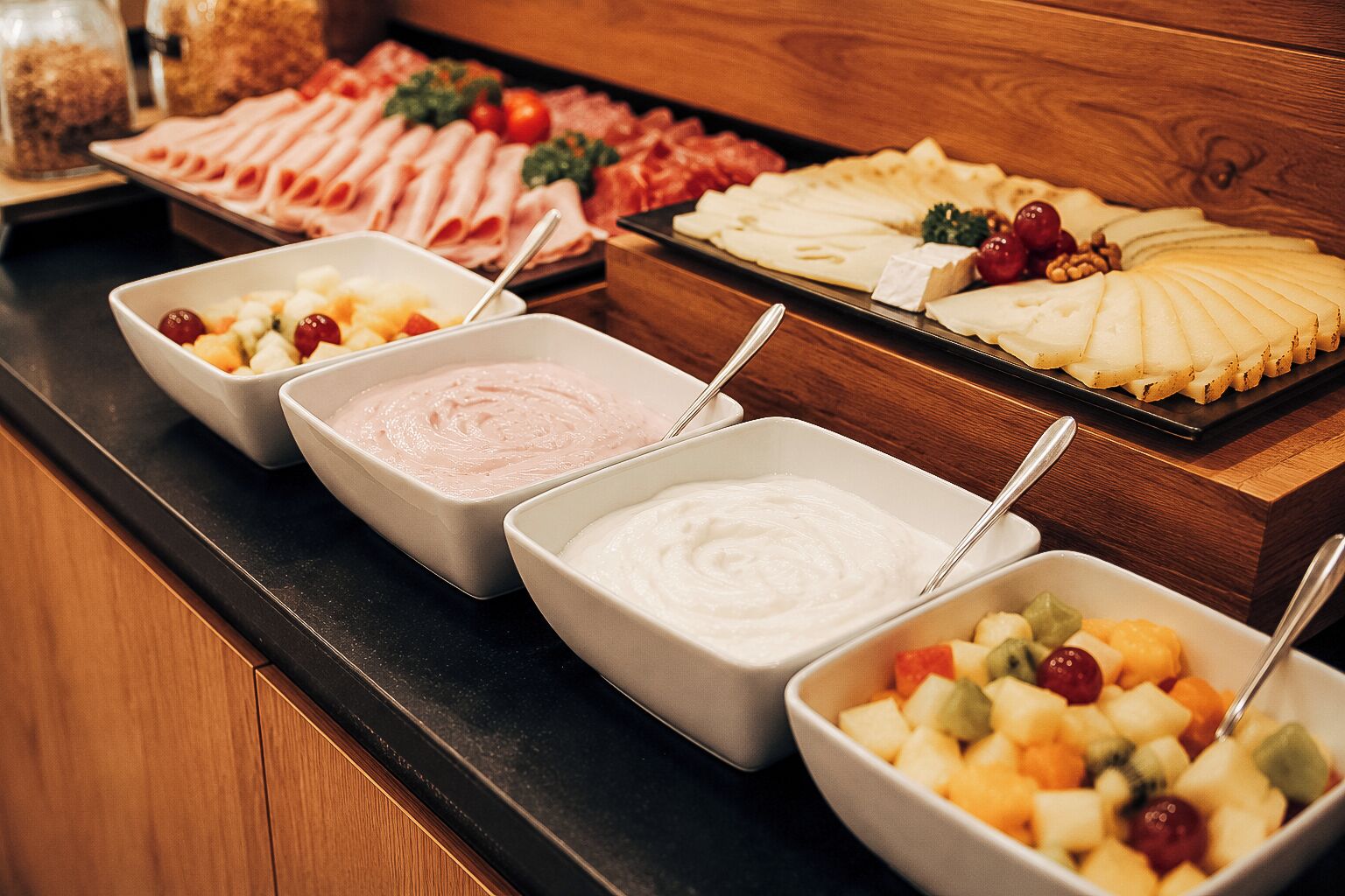 Un bufé con una variedad de alimentos, incluyendo carnes, quesos y frutas.
