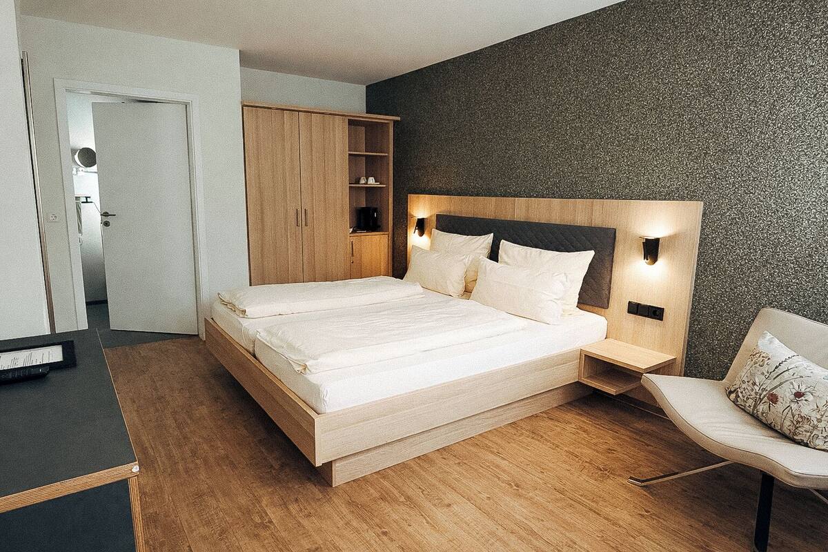 A modern bedroom with a wooden bed, built-in wardrobe, and a nightstand with a lamp.