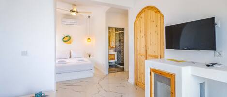 A modern bathroom with a white vanity, a mounted TV, and a wooden door.