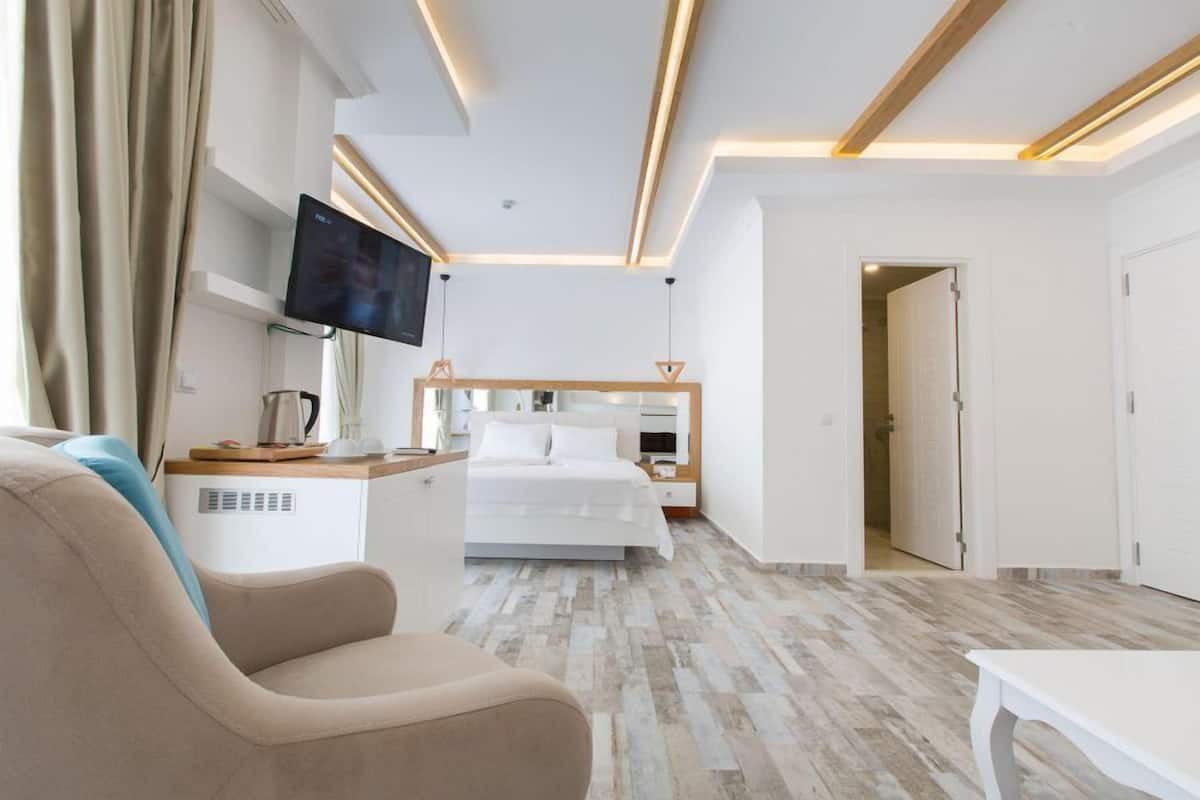 A modern hotel room with a bed, a TV, a desk, and a seating area.