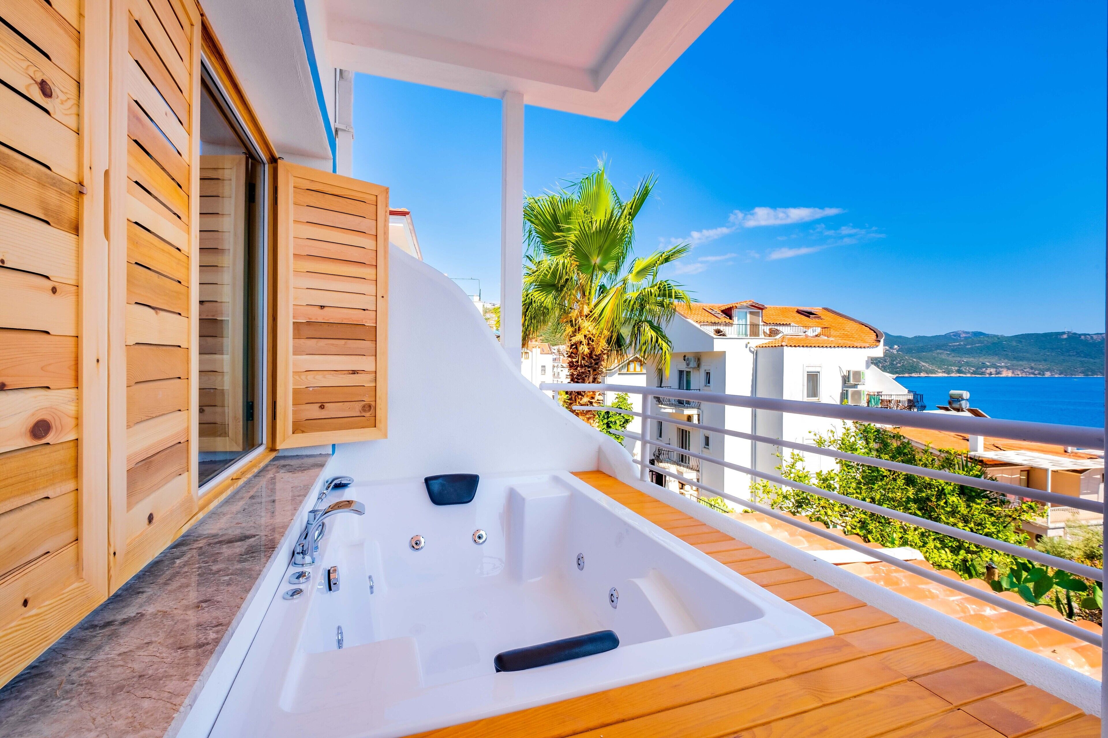 Un balcón con piso de madera y una bañera jacuzzi blanca.