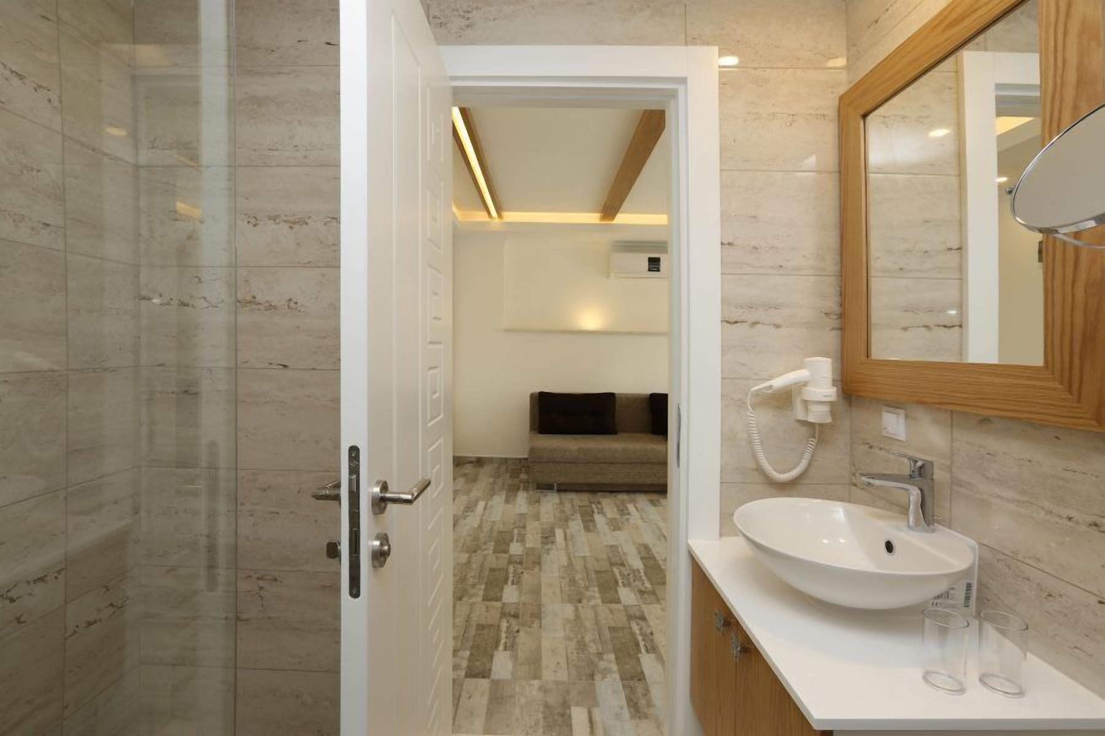 Une salle de bain moderne avec une douche à l’italienne en verre, un lavabo blanc et un meuble-lavabo en bois.