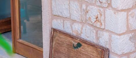 Letrero del Hotel Payam sobre una pared de piedra, un cofre de madera, una silla amarilla y un taburete de madera.