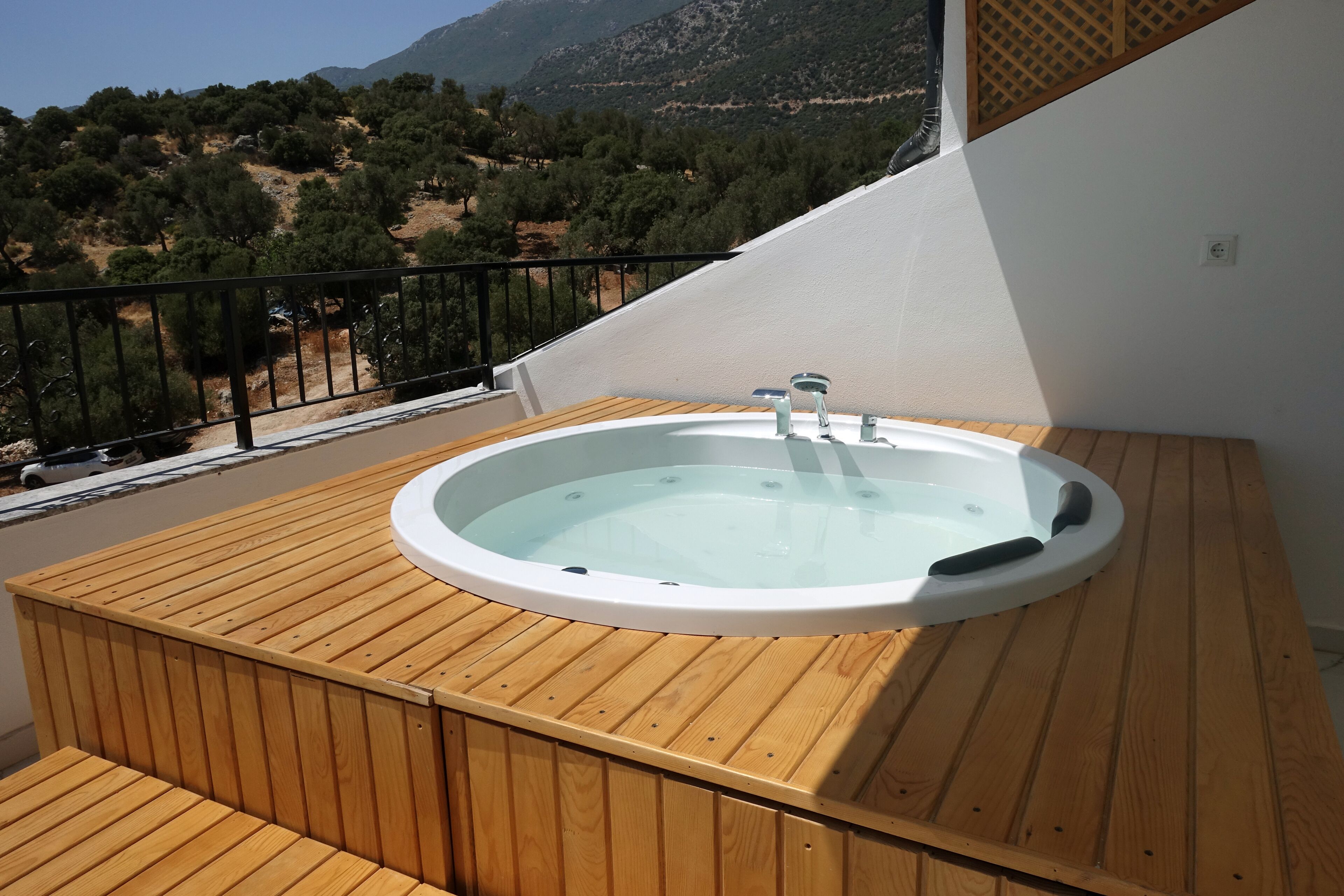 A wooden deck with a hot tub and a view of a mountainous landscape.