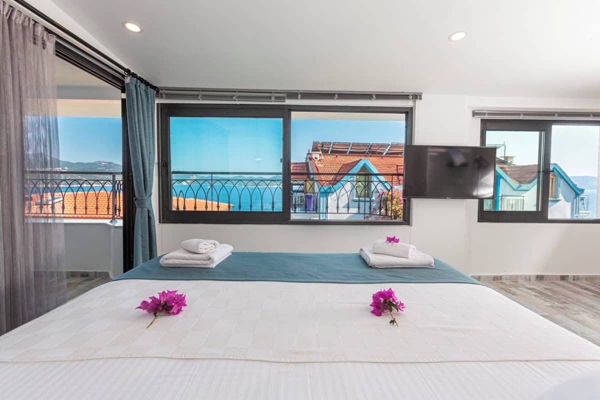 A hotel room with a large bed, two towels, and two flowers on the bed.