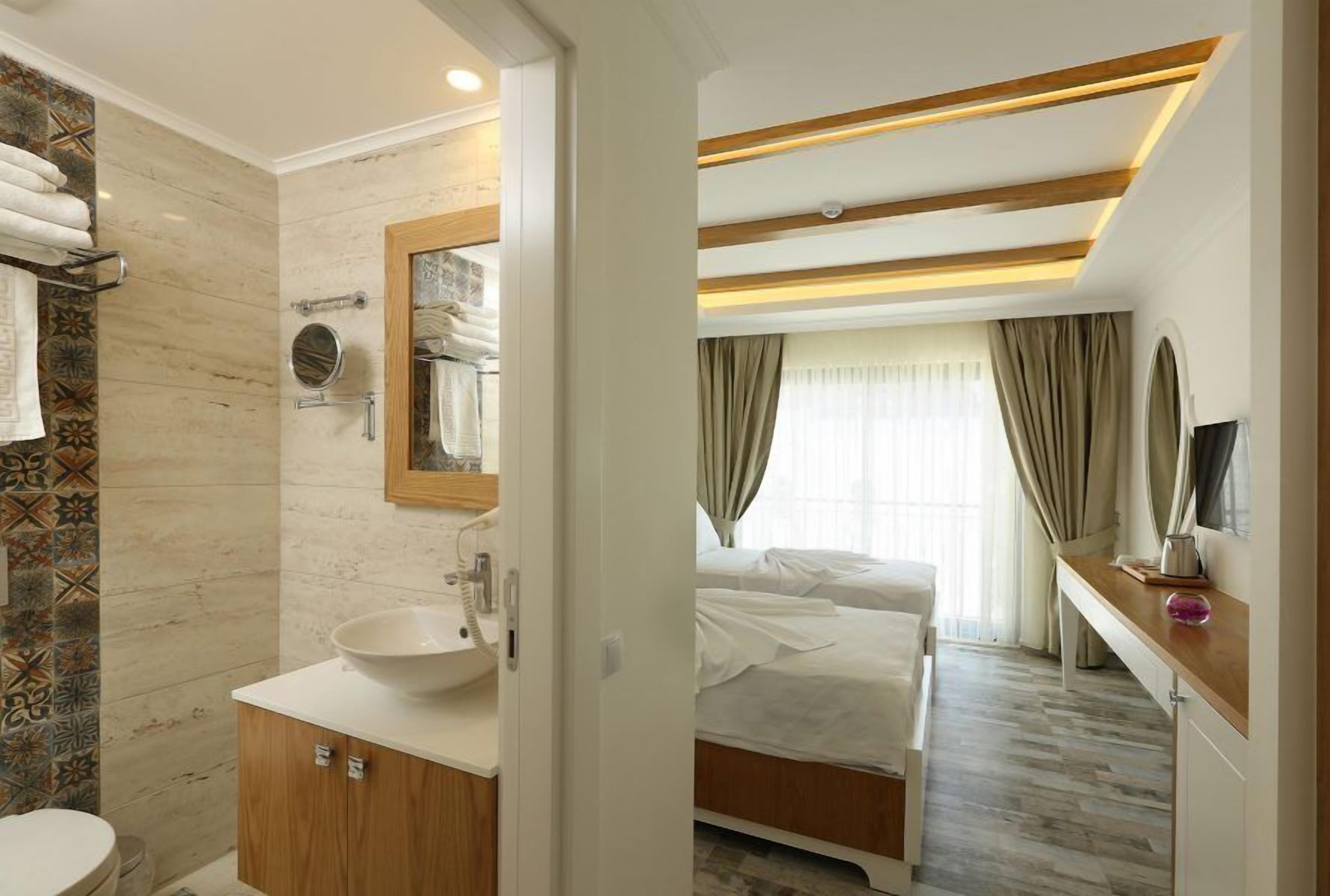 A hotel room with a bathroom, a bed, and a bedside table.