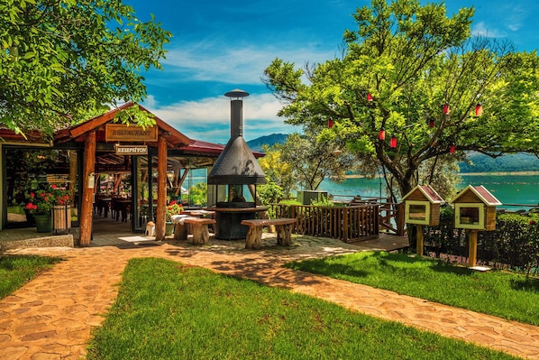 Un restaurante con terraza, una chimenea decorativa y vistas a un lago.