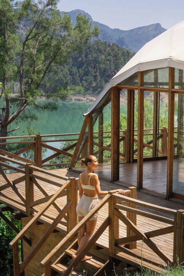 Una terraza de madera con vistas a un lago y montañas.