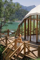 Una terraza de madera con vistas a un lago y montañas.