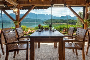 Una mesa de madera con sillas, con vistas a montañas y un lago.