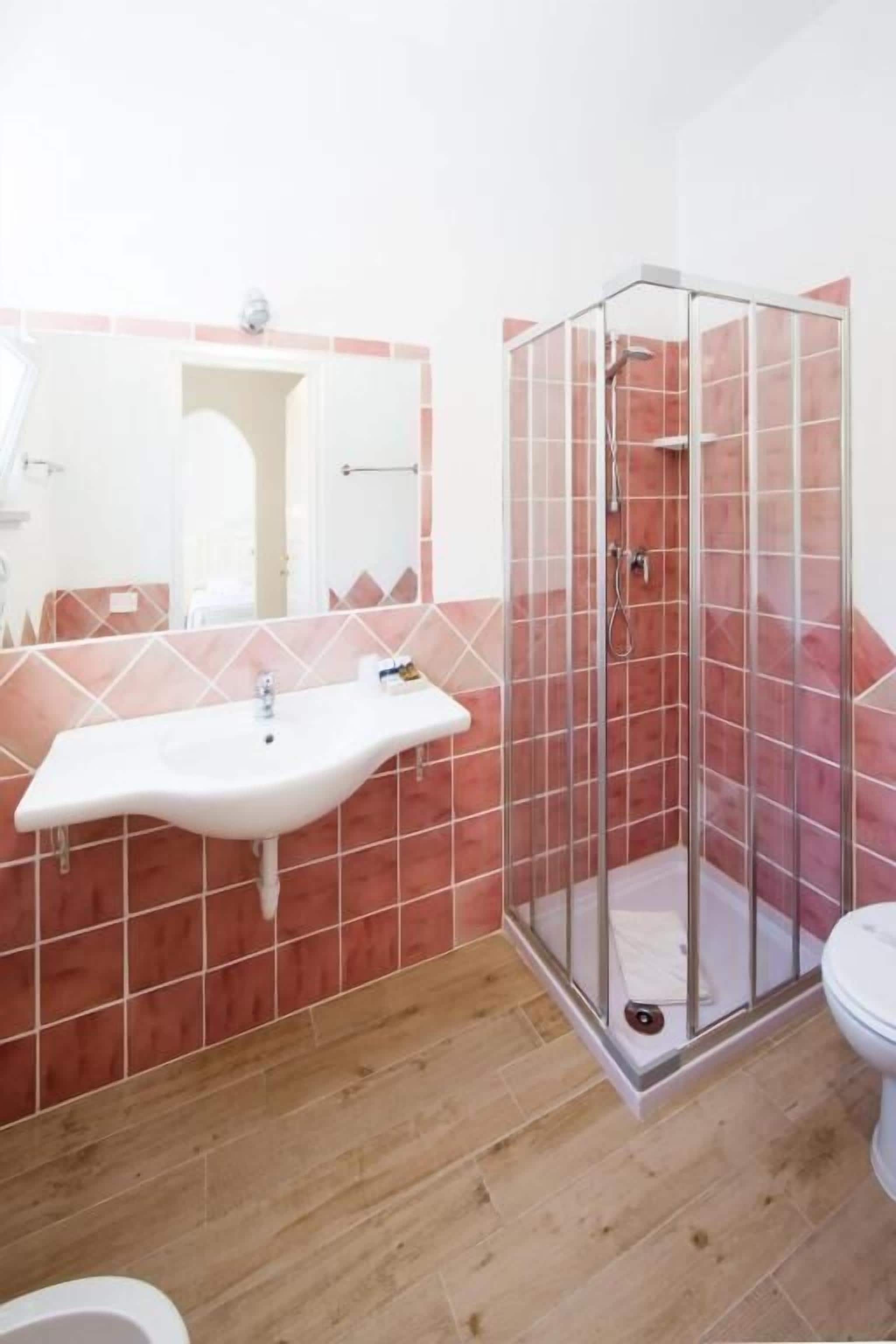 A bathroom with a white sink, a glass shower enclosure, and a toilet.